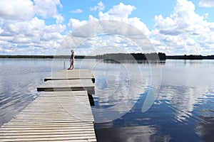 Teenage girl standing on a dock on a lake in Finland