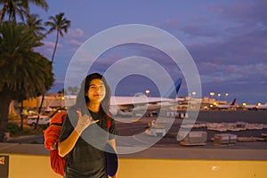 Teenage girl standing at Hawaiian airport making shaka sign