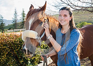 Teenage girl standing with her chestnut Arab horse looking at the camera