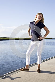 Teenage girl standing posed on dock by water