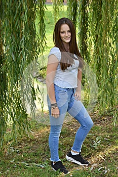 Teenage girl stands near a weeping willow