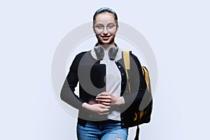 Teenage girl student with backpack holding laptop on white studio background