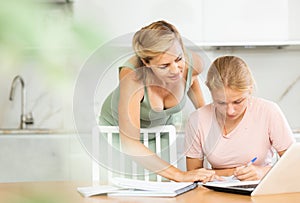 Teenage girl studying at home guided by friendly female tutor