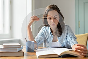 Teenage girl studying reading book at home