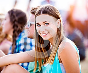 Teenage girl at summer music festival, sitting on the ground