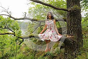 Teenage girl in summer sitting on branch