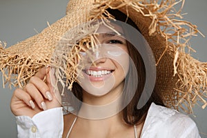 Teenage girl with sun protection cream on her face against grey background