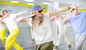 Teenage girl in sunglasses and cap training breakdance Toprock moves in dance hall