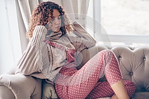 Teenage girl in sweater and jumpsuit on a couch