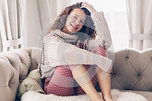 Teenage girl in sweater and jumpsuit on a couch