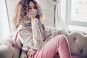 Teenage girl in sweater and jumpsuit on a couch