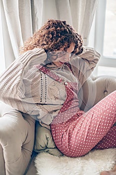 Teenage girl in sweater and jumpsuit on a couch