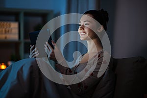 teenage girl with tablet pc in bed at night