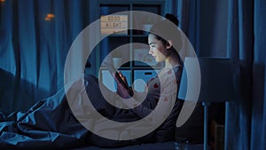 teenage girl with tablet pc in bed at night