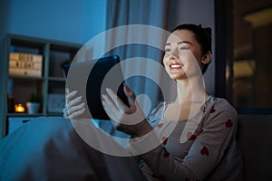 teenage girl with tablet pc in bed at night