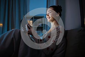 teenage girl with tablet pc in bed at night