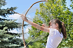 Teenage girl taking aim with a bow and arrow