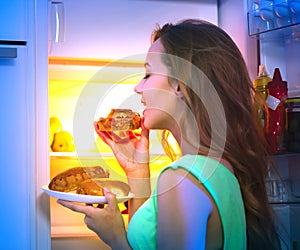 Teenage girl taking food from refrigerator at night