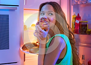 Teenage girl taking food from refrigerator at night