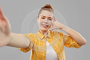 Teenage girl taking selfie making calling gesture