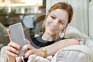 Teenage girl taking a selfie with a smart phone smiling sitting at home
