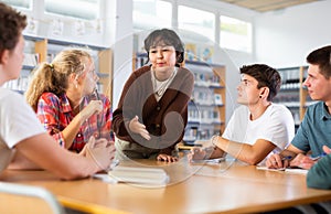 Teenage girl tells an interesting story to his friends in school library