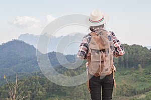 Teenage girl tourists stand and look at the beautiful mountain landscape, strolling with a relaxing backpack on top of the cliff