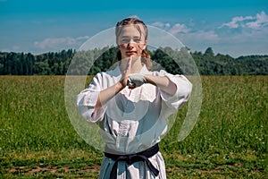 Teenage girl training karate kata outdoors, greetings oss photo