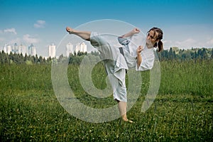 Teenage girl training karate kata outdoors, performs the uro mawashi geri hook kick