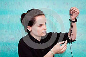 A teenage girl tries to untangle the wires from her headphones