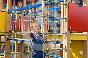 Teenage girl try to climbing on the rope wall. She is playing with the rope wall to develop motor activity at the playground