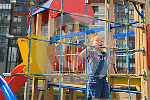 Teenage girl try to climbing on the rope wall. She is playing with the rope wall to develop motor activity at the playground