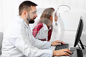 Teenage girl udergoes eye survey with doctor on tomograph