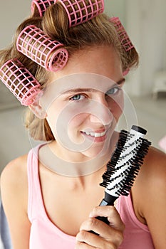 Teenage girl using curlers in her hair