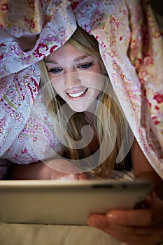 Teenage Girl Using Digital Tablet In Bed At Night