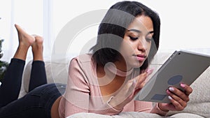 Teenage girl using digital tablet on sofa