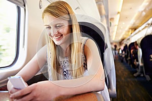 Teenage Girl Using Mobile Phone On Train Journey