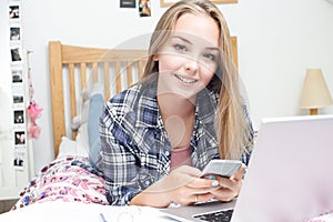 Teenage Girl Using Mobile Phone Whilst Doing Homework