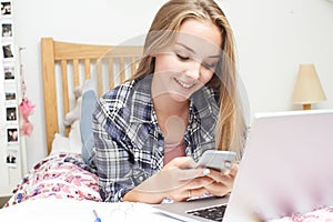 Teenage Girl Using Mobile Phone Whilst Doing Homework