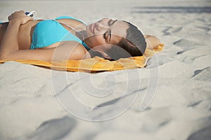 Teenage Girl Using MP3 Player Lying On Beach Towel