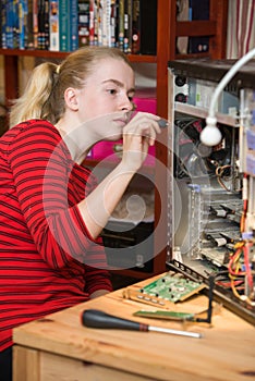 Teenage girl using a screwdriver to dismantle an open PC