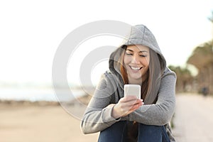 Teenage girl using a smart phone on the beach