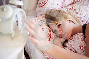 Teenage Girl Waking Up In Bed And Turning Off Alarm Clock