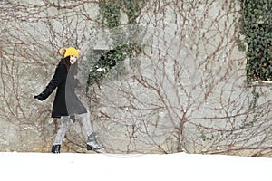 Teenage girl walking in front of grey wall in snow