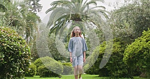 Teenage girl walking on grassy field against trees at park