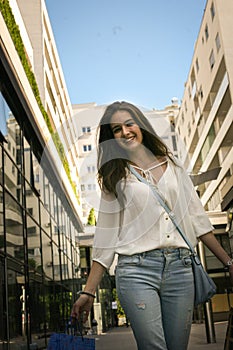 Teenage girl walking street with shopping bags poses to camera.