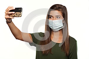 Teenage Girl Wearing a Surgical Mask with a Smart Phone Taking a Selfie of Herself
