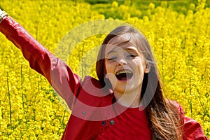 Teenage girl welcomes spring in a field with yellow rapeseed flowers