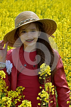 Teenage girl welcomes spring in a field with yellow rapeseed flowers