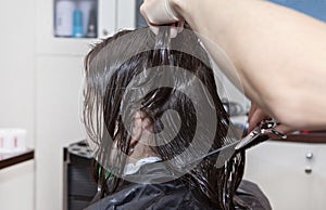 A teenage girl with wet hair during the haircut process